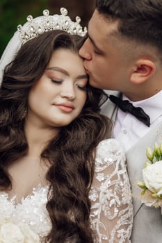 A bride and groom are kissing each other's faces photo