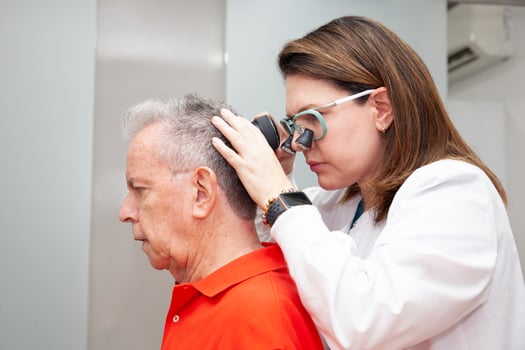 Dermatologist performing a trichoscopy to a senior male patient. photo