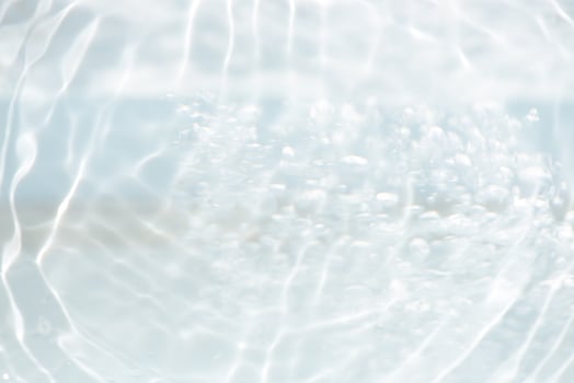 Bluewater waves on the surface ripples blurred. Defocus blurred transparent blue colored clear calm water surface texture with splash and bubbles. Water waves with shining pattern texture background. photo