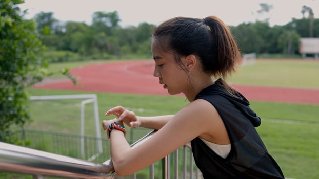 A woman wearing a smart watch is standing on a grassy field photo