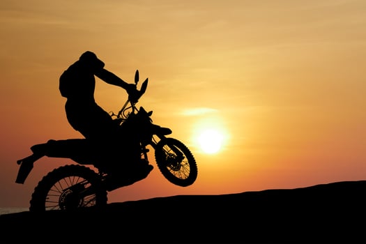 Silhouette of a Motorcyclist Performing a Wheelie Against a Stunning Sunset Background photo