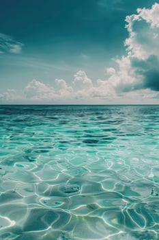 Calm, clear ocean water under a blue sky with white clouds. Vertical background photo