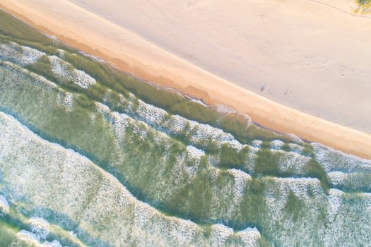 shore of a deserted beach at sunrise aerial view from a drone, foam from waves at high tide photo