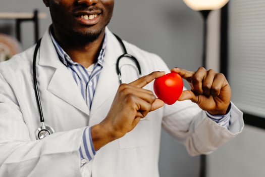 Man in white lab coat holding red heart photo
