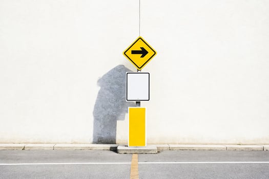 White wall with blank sign and yellow arrow sign photo