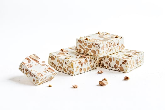 Stacked nougat with almonds on white background photo