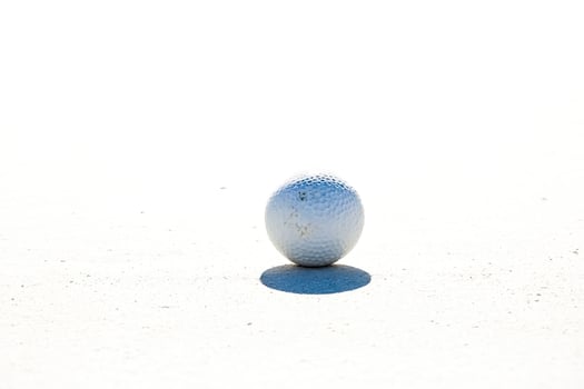 Golf ball on white sand photo