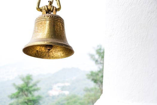 Golden Bell Hanging Against a White Wall photo
