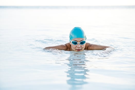 Woman in blue swimming cap and goggles swimming in water photo