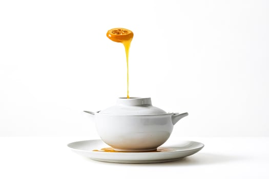 Honey dripping from a slice of orange into a white teapot photo