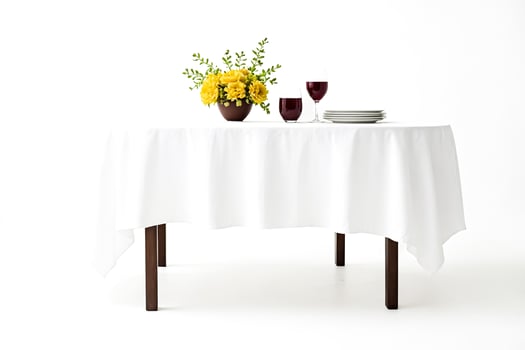 White Tablecloth on Round Table with Yellow Flowers, Wine Glasses, and Plates photo