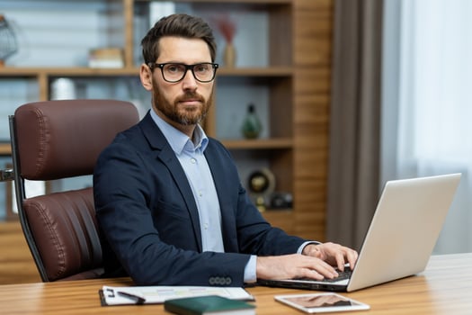 Focused mature man in stylish office working on laptop. Business professional, lawyer, or banker in a home environment. photo
