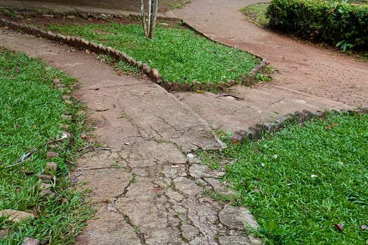 T junction or pertigaan damaged stone concrete country side road walk way isolated on horizontal green grass background. photo