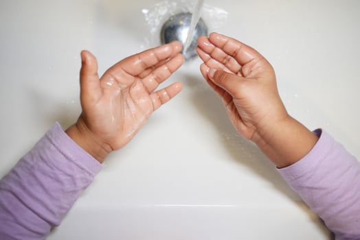child making a cleansing gesture with soap and water on hands photo