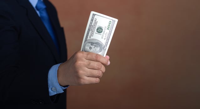 Hand of a businessman holding US dollars while standing with a brown background. Personal loans or business loans. Space for text. Close-up photo. Business and finance concept photo