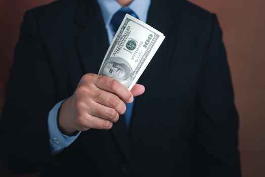 Hand of a businessman holding US dollars while standing with a brown background. Personal loans or business loans. Space for text. Close-up photo. Business and finance concept photo