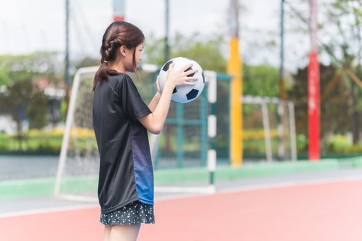 Asian child girl playing football in the urban outdoor futsal court photo