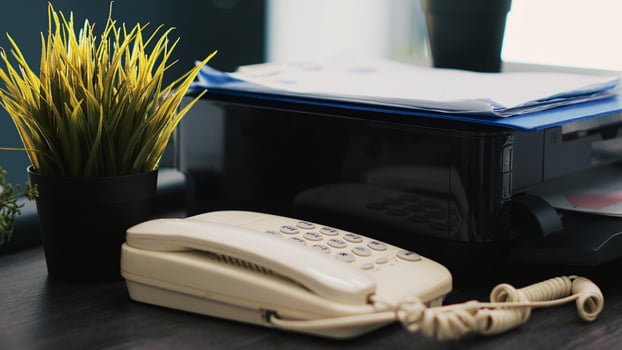 Company paperwork on top of printer, telephone and mini house plants on office desk close up. Business documents, printing machine and phone on table in accounting workplace photo