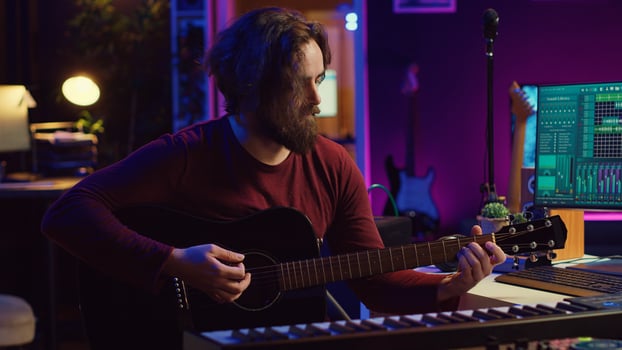 Portrait of male songwriter playing acoustic guitar and recording musical sounds to use for mix and master in home studio. Composing tunes with digital audio workstation software. Camera A. photo