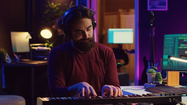 Young artist composing a song on electronic piano keyboard at home recording studio. Audio engineer playing MIDI controller, working on producing a soundtrack, soundboard tools. Camera A. photo