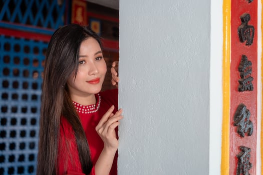 Vietnamese girl with Ao Dai dress standing in traditional house of Vietnam. Text in photo mean best wishes to family, happiness, prosperity, health. Tet holiday and New Year.