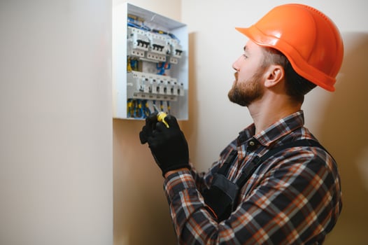 handsome young man electrician working on switchboard of house building construction site photo