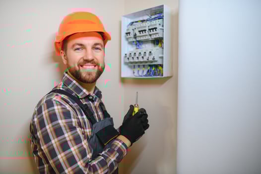 handsome young man electrician working on switchboard of house building construction site photo