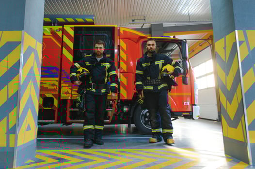 Two firefighters in protective clothing in helmets with fire engine photo