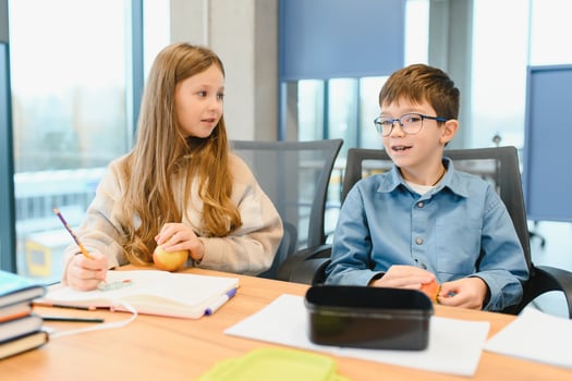 Multiracial schoolchildren having lunch at the desk during a break in school photo