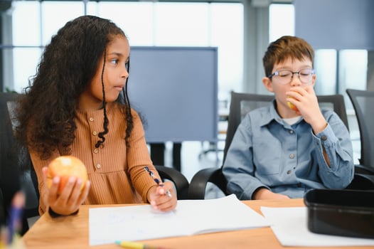 Multiracial schoolchildren having lunch at the desk during a break in school photo