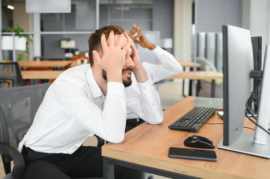 Two Unhappy tired businessman, corporate manager, sits at the workplace, tired from online work, stressed, nervous, massages the bridge of his nose, closed his eyes, experiencing a headache photo