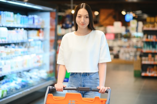 Young smiling happy woman 20s in casual clothes shopping at supermaket store with grocery cart photo