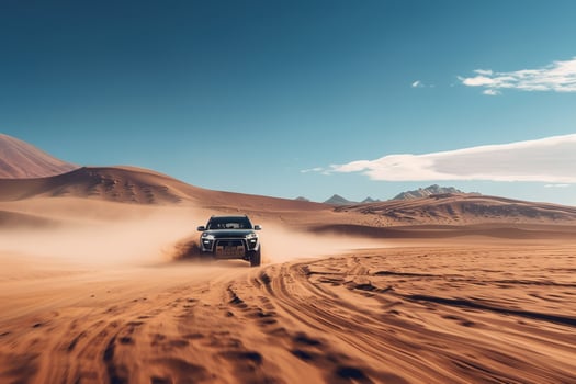 Electric SUV driving on an off road path through desert landscape with sand dunes and clear blue skies photo