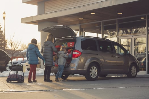 Versatility Family minivan parked at suburban shopping mall with parents loading groceries into the trunk and children getting into the back seats Background photo
