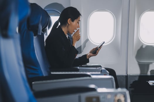 Business woman uses mobile phone and laptop to chat with friends sitting in airplane. photo