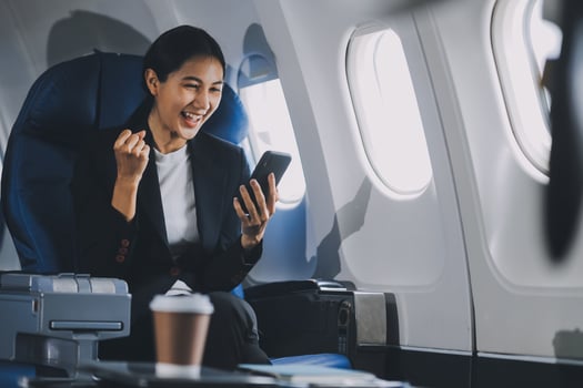 Business woman uses mobile phone and laptop to chat with friends sitting in airplane. photo
