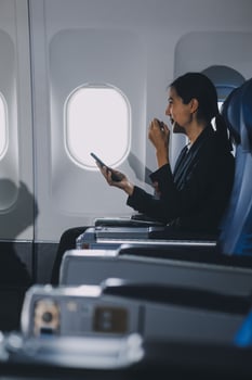 Business woman uses mobile phone and laptop to chat with friends sitting in airplane. photo