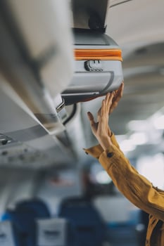 Young Female Tourist Storing Luggage in Overhead Compartment on Airplane During Travel photo
