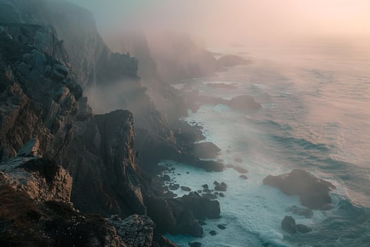Landscape Ethereal misty morning on coastal cliffside with waves crashing against rocky shores and glow on the horizon   nature background photo