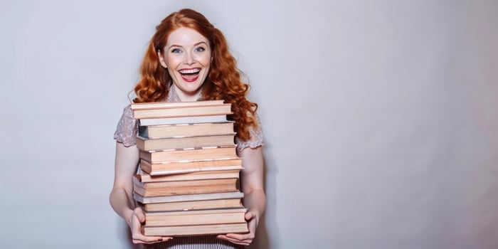 A smiling woman is holding a stack of books against a white background photo