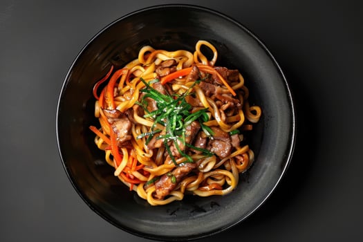 Udon Noodles with Pork, Carrots, and Green Onions in a Black Bowl photo