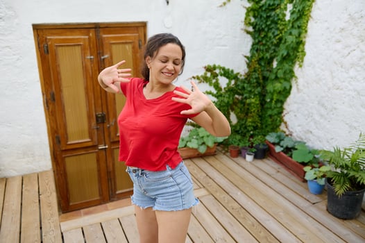 Happy woman dancing outdoors on a wooden deck with rustic door and green plants background photo