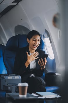 Business woman uses mobile phone and laptop to chat with friends sitting in airplane. photo