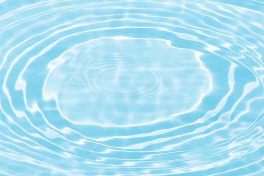 Bluewater waves on the surface ripples blurred. Defocus blurred transparent blue colored clear calm water surface texture with splash and bubbles. Water waves with shining pattern texture background. photo