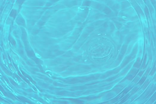 Bluewater waves on the surface ripples blurred. Defocus blurred transparent blue colored clear calm water surface texture with splash and bubbles. Water waves with shining pattern texture background. photo
