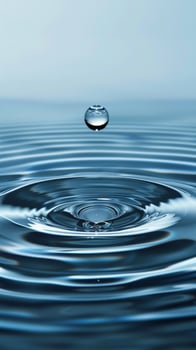 A single water droplet falls into still water, creating concentric ripples photo