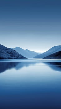 A still lake reflecting a mountain range under a clear, blue sky photo