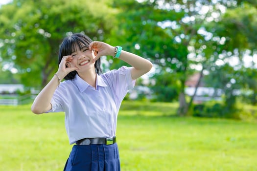 Portrait cute lovely happy Asian student school uniform girl in at green park outdoor pretty hand photo