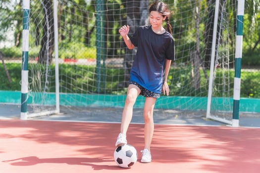 Asian child girl playing football in the urban outdoor futsal court photo