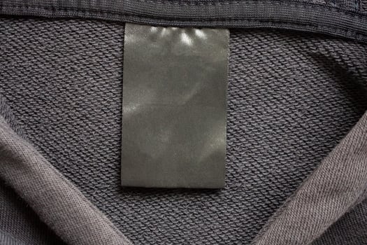Blank black laundry care clothes label on black fabric texture background photo